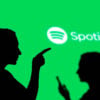 The silhouettes of two people in front of a bright green background with a Spotify logo